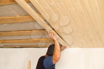 worker working on a wooden ceiling in the house .