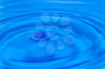 a drop of water falling in blue water. macro