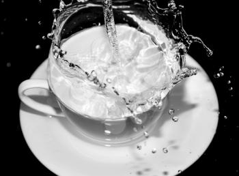 water in the cup with splashes on a black background