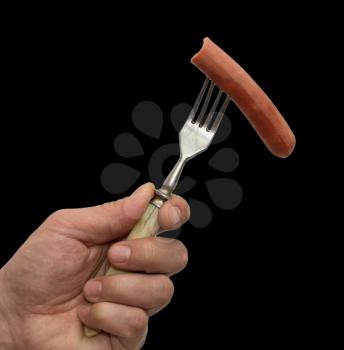 sausage on a fork in his hand on a black background
