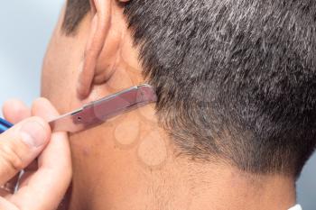 Hairdresser shaving man's neck with a straight razor