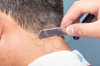 Hairdresser shaving man's neck with a straight razor