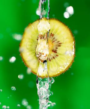 kiwi fruit in a spray of water on a green background