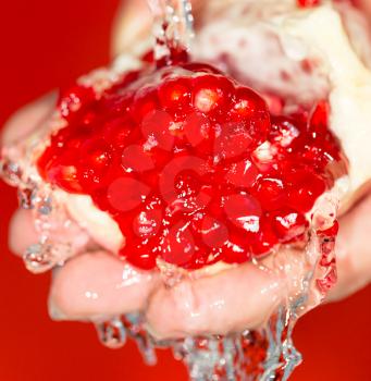 Ripe red pomegranate in her hand in water