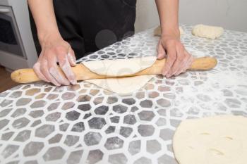 sheeting the dough with a rolling pin in the kitchen
