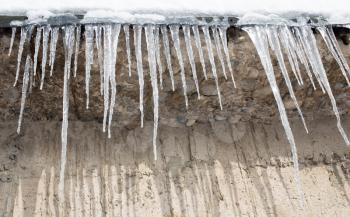 Large icicles hanging on the roof of the house in springtime