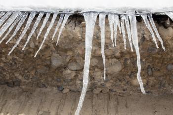 Large icicles hanging on the roof of the house in springtime