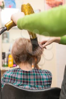 Hairdresser dries the hair dryer blond  hair