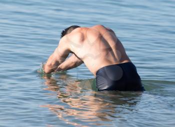 man bathes in the lake on the beach