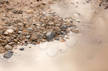 Puddle on the road with stones as background .