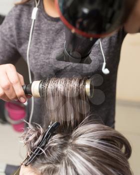 Styling female hair dryer in the beauty salon .