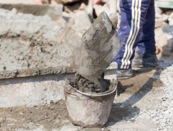Worker with a bucket of concrete on a construction site .
