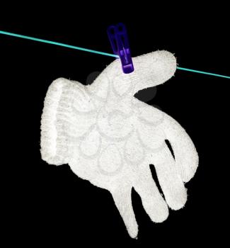 The glove is dried on a rope on a black background .