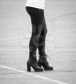 Legs of a girl in black pantyhose walking along the road .