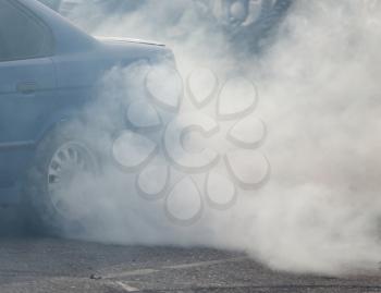 Smoke from under the wheels of the car .