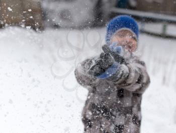 Boy playing with snow on nature in winter
