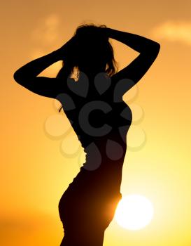 Silhouette of a beautiful girl at sunset .