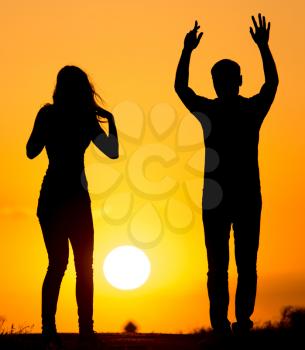Silhouette of a guy and a girl at sunset .