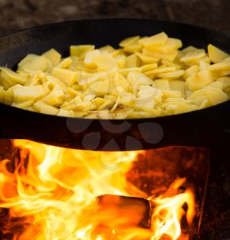 Potatoes fried in a frying pan in the open air .