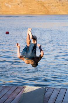 A man dives from shore to lake .