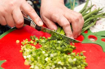 Cook cuts green onions with a knife .