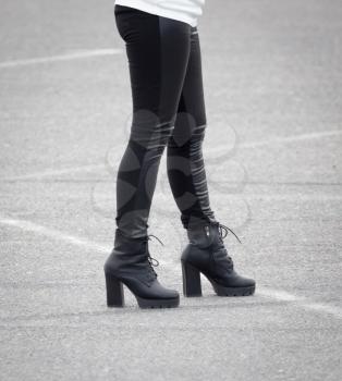 Legs of a girl in black pantyhose walking along the road .