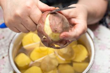The cook cleans the potatoes with a knife .