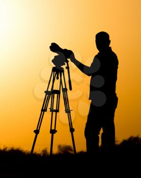 Man photographer with a camera at sunset .