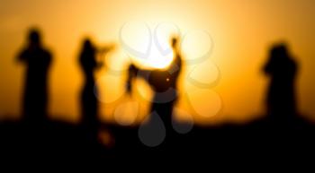 Blurred silhouettes of people with cameras at sunset .