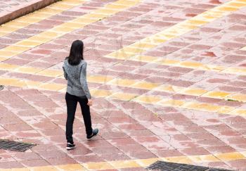 The girl is walking along paving stones .