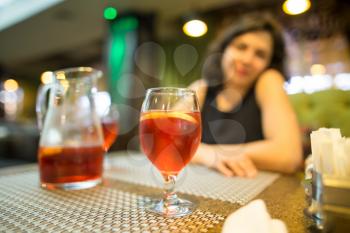 A girl drinks a red strawberry drink in a restaurant .