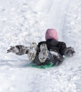 The child rolls down the hill in winter .