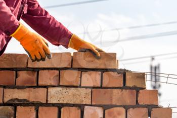 Worker builds a brick wall in the house .