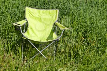 Green folding chair is on the grass