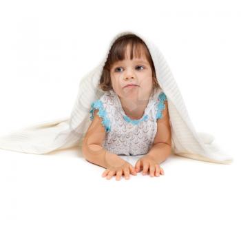 Thoughtful little girl lying on the floor wrapped in a light blanket. Isolate on white.