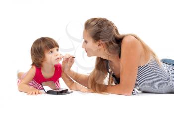 Young mother paints lipstick little daughter in the studio on a white background