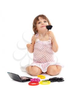 Charming little girl with makeup and colored beads in the studio sitting on the floor. Isolate on white.