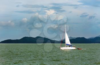 white sailboat in the background of the tropical islands of the Andaman Sea
