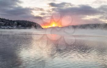 Frosty mist over the lake with the setting sun