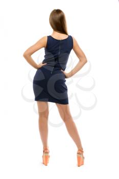 Slim girl in a dress stands back. Isolated on white background