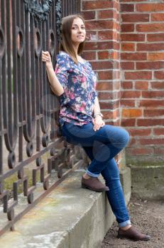 Full-length portrait of a pensive girl near old fence,