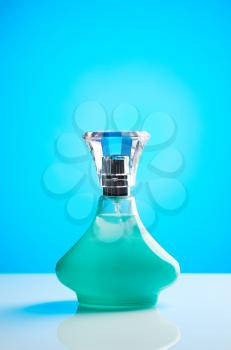 Green bottle of perfume for women with blue gradient background light spot.