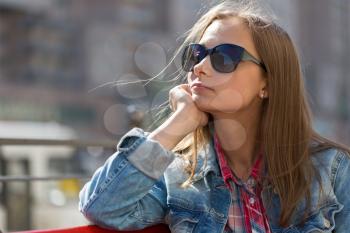 Portrait in profile of a young beautiful pensive girl in sunglasses looking into the distance