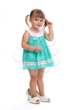 Little three year old girl in her mother's shoes in the studio on a white background.