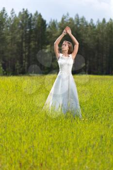 girl in a wedding dress relaxes with her eyes closed in the field.