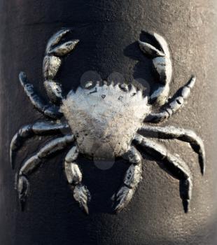 Pattern crab on a cast iron post in the light of the sun. Close-up.