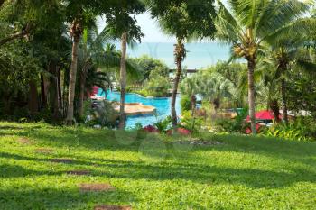 Green grass area with palm trees swimming pool at east coast of Thailand.