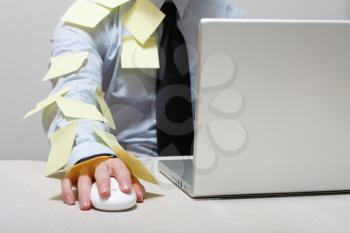 Royalty Free Photo of a Man Covered in Yellow Notes by a Laptop
