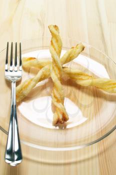 puff pastry sticks on a glass transparent plate over pine wood table