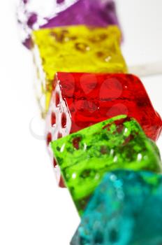 bounch of colorfull translucent dice shaped lollipops backlit on white background